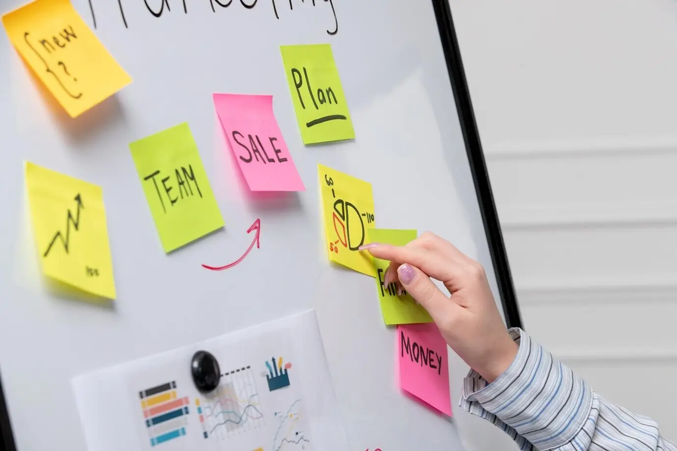 Jeune et mignonne femme d’affaires spécialisée en marketing, portant une chemise à rayures, au bureau, expliquant un diagramme en secteurs sur un tableau.
